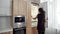 Making your life easier. Young afro american house maid in uniform cleaning refrigerator in the modern kitchen. Cleaning