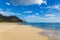 Makua beach view with beatiful mountains and a sailboat in the background, Oahu island