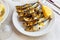 Malaga cuisine grilled sardines served with lemon on white plate on wooden table