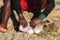 Malagasy fisher cleaning freshly caught porcupine pufferfish on the beach, detail as sun shine over his bare feet and