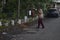 malang, indonesia -17 april, 2021: an old man sweeps the asphalt road with a long-handled broom stick