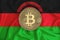 Malawi flag, bitcoin gold coin on flag background. The concept of blockchain, bitcoin, currency decentralization in the country.