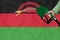 MALAWI flag Close-up shot on waving background texture with Fuel pump nozzle in hand. The concept of design solutions. 3d