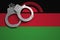 Malawi flag and police handcuffs. The concept of crime and offenses in the country