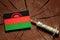 Malawi flag on a stump with syringe injecting money