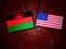 Malawi flag with USA flag on a tree stump