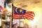 Malaysia Flag Against City Blurred Background At Sunrise Backlight