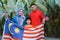 Malaysian family holding malaysia flag in front of their house