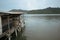 A Malaysian house on stilts sitting on top of a body of water. It is built with planks and zinc roof