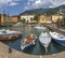 MALCESINE, ITALY - JUNE 13, 2019: The little harbor on the waterfront of Lago di Garda lake with the 2000 m high mountains in the