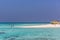 Maldives, Feb 8th 2018 - Tourists swimming in a turquoise blue sea, desert island, small traditional hut hotel on a blue sky day,