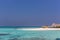 Maldives, Feb 8th 2018 - Tourists swimming in a turquoise blue sea, desert island, small traditional hut hotel on a blue sky day,