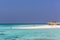 Maldives, Feb 8th 2018 - Tourists swimming in a turquoise blue sea, desert island, small traditional hut hotel on a blue sky day,