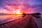 Maldives island sunset landscape. Colorful clouds and sky with luxury water villas and long wooden pier