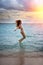 Maldives. The silhouette the slender young woman happily jumps in the sea on a sunset