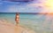 Maldives. The young slender woman goes in a bathing suit on shallow water of the sea