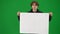 Male activist holding a large blank placard. Man protesting in studio on green screen close up.