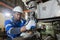 Male African American workers wearing uniform safety and hardhat working an iron cutting machine in factory Industrial.