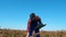 Male agriculturist walks on a field with crops, holding a laptop.