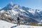 Male alpinist standing on the snowy ground in the mountains dressed in warm clothes and backpack