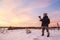 Male amateur photographer takes pictures of colorful winter sunset. Winter wonderland with purple colors