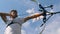 Male archer training with a bow on a shooting range.