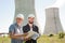 Male architects reviewing documents together at electric power plant.