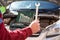 Male arm holding steel wrench for car repair. Vehicle engine is on background