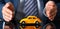 Male arm in suit and tie cover yellow toy car