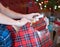 Male arms and hands opening Christmas present with blurry tree lights in background