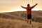 Male with arms raised at sunset. Young happy man at sunset raises hands up