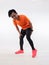 Male Asian runner having rear leg pain, hamstring muscle cramp because of not doing warm up before run exercise. High key studio