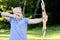 Male Athlete Aiming With Bow And Arrow In Forest