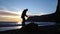 A male athlete doing a back somersault and landed on his feet on the beach, side view in slow motion. Nature summer