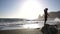 A male athlete doing a back somersault and landed on his feet on the beach, side view in slow motion. Nature summer