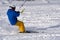 A male athlete engaged in snow kiting on the ice of a large snowy lake. He goes skiing in the snow.