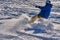 A male athlete engaged in snow kiting on the ice of a large snowy lake. He goes skiing in the snow.