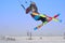 A male athlete engaged in snow kiting on the ice of a large snowy lake. He performs the jump. Winter sunny frosty day