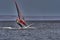 A male athlete is interested in windsurfing. He moves on a Sailboard on a large lake