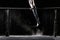 Male athlete performing handstand on gymnastic parallel bars with talcum powder. on black.