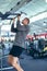 Male athletic exercising on pull-up machine in fitness center