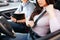 Male auto instructor takes exam in young woman. Cut view of brunette locking seat belt with hand. Seating at place with