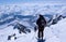 Male backcountry skier skiing down from a high alpine summit with a large backpack and solar panel