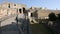 Male backpacker going up stone walkway towards entrance of Pompeii on sunny day