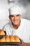 Male Baker Holding Fresh Breads In Baking Tray