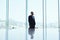 Male banker is standing in modern office interior and watching in window on business district