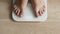 Male bare feet stepping on white digital floor scales - man weighing himself at home: close up top view. Measuring