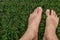 Male bare feet walk on green grass. Summer walk barefoot on the lawn. 3D illustration