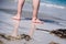 Male bare feet in a warm sand, man taking a walk on a sunny beach with turquoise water during vacation