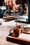 Male barista pouring expresso coffee into shot glass, making pour-over coffee with alternative method called Dripping